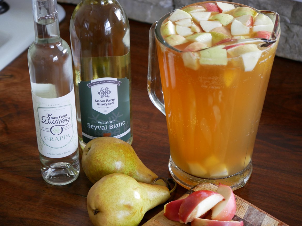 fall sangria with fruit pitcher and bottles of grappa wine